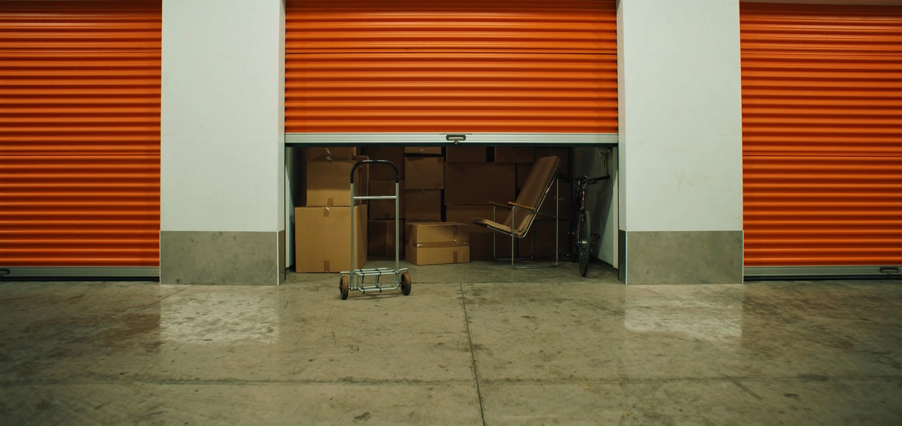 Box de self-storage aberto com caixas de mudança organizadas e um carrinho de carga